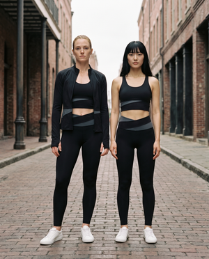 Two models wearing the Gilded Streets Paneled Performance set in black, New Orleans Warehouse District